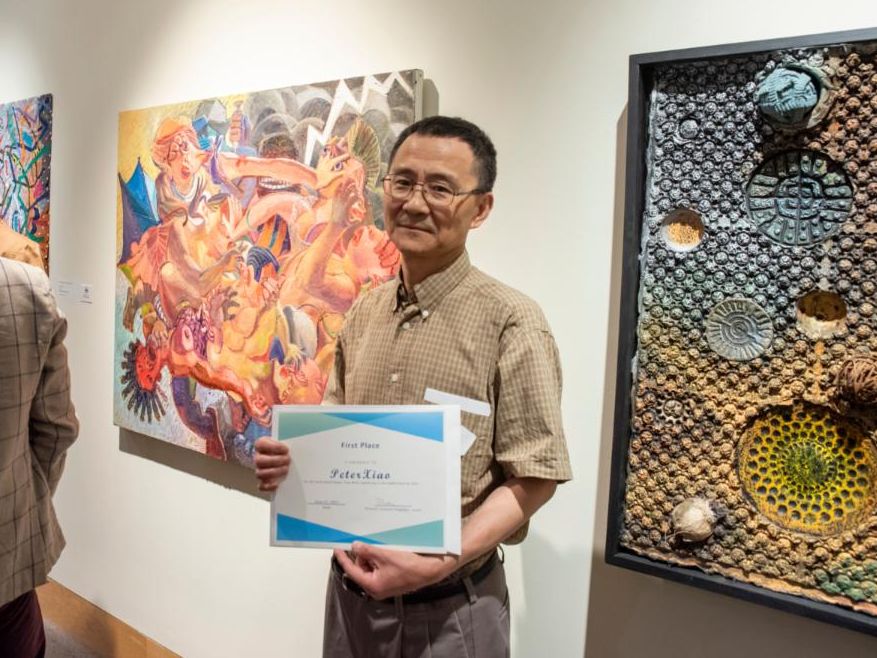 Peter Xiao stands next to his painting "Rumor Tree with Lightning."