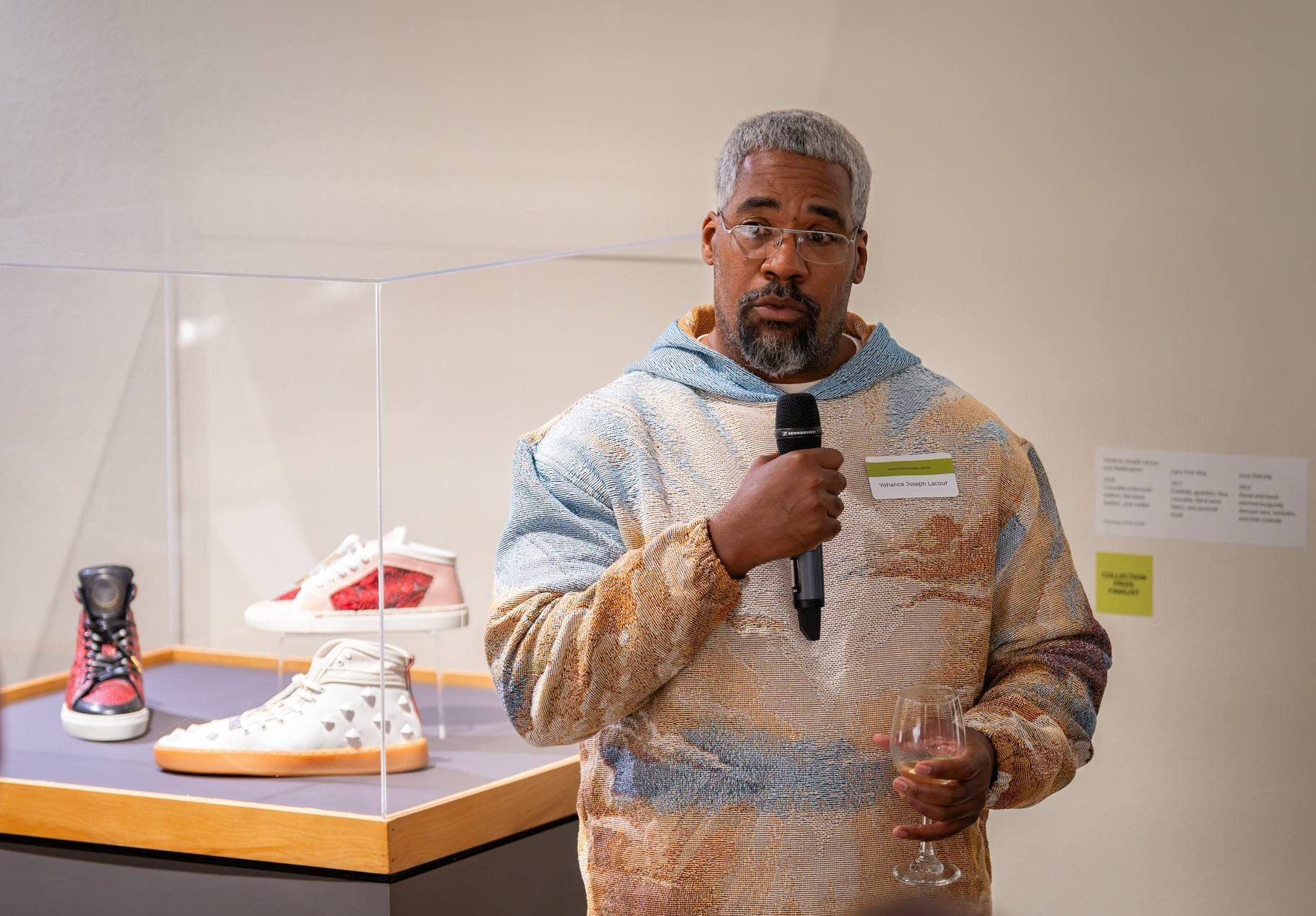 Yohance Lacour speaks in in the exhibition gallery in front of his work.